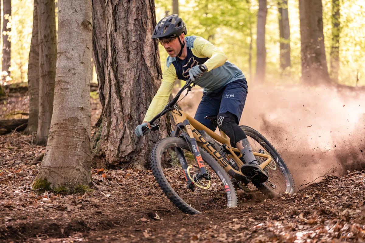 A mountain biker kicks up dust on a forest trail.